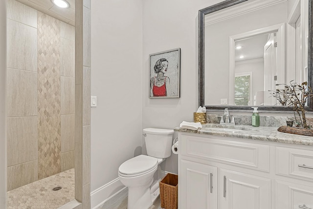 bathroom featuring a tile shower, vanity, crown molding, and toilet