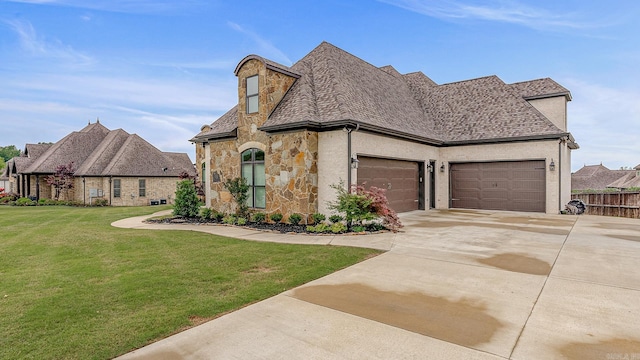 french provincial home with a front yard and a garage