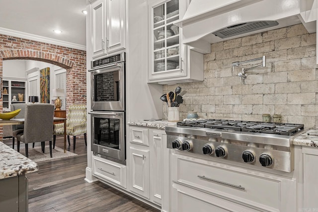 kitchen with ornamental molding, stainless steel appliances, white cabinets, and extractor fan