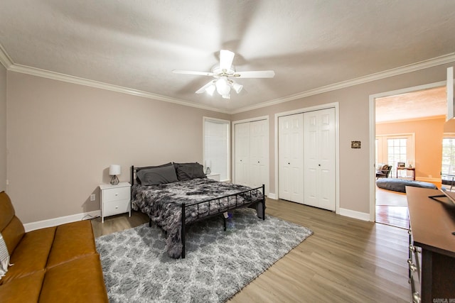 bedroom with wood-type flooring, two closets, ornamental molding, and ceiling fan