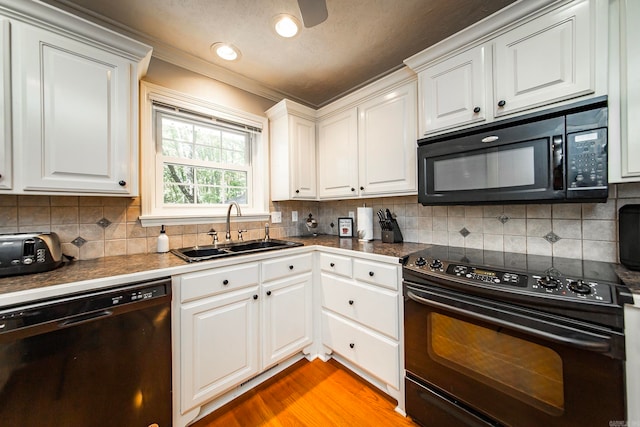 kitchen with black appliances, white cabinetry, and sink