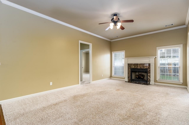 unfurnished living room featuring ceiling fan, light colored carpet, crown molding, and a premium fireplace