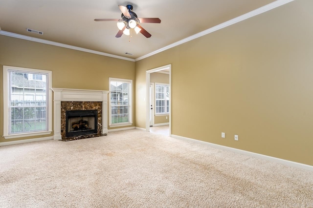 unfurnished living room featuring ceiling fan, light colored carpet, crown molding, and a premium fireplace