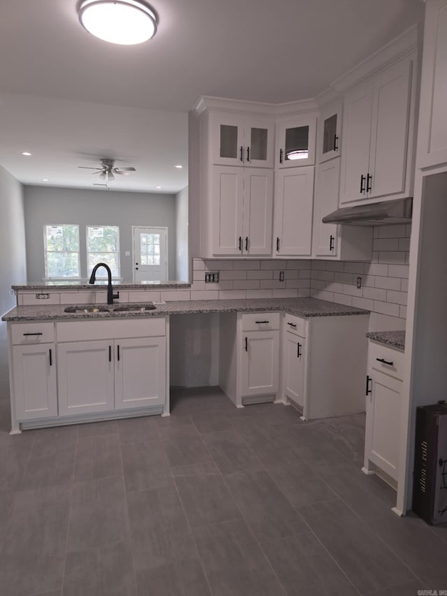 kitchen with stone counters, white cabinetry, ceiling fan, and sink