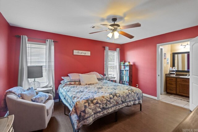 bedroom featuring ceiling fan, ensuite bathroom, light wood-type flooring, and sink