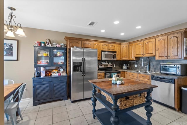 kitchen with light tile patterned floors, sink, stainless steel appliances, a notable chandelier, and decorative backsplash