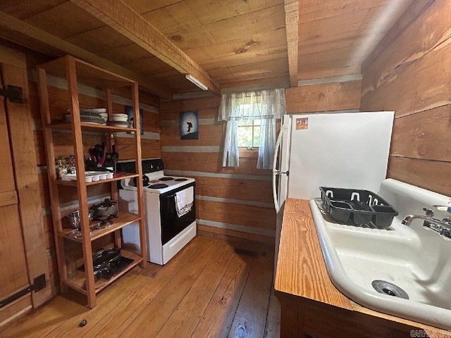 kitchen with wood ceiling, wood walls, sink, white appliances, and hardwood / wood-style floors