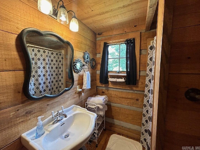 bathroom featuring wooden walls, wooden ceiling, and sink