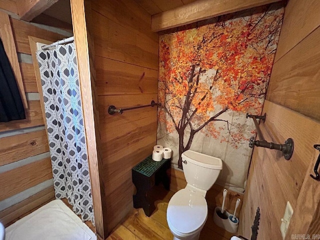 bathroom featuring wooden walls, a shower with curtain, wood-type flooring, and toilet