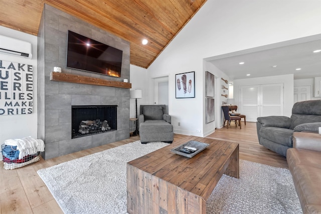 living room with a fireplace, light hardwood / wood-style flooring, high vaulted ceiling, a wall mounted AC, and wooden ceiling