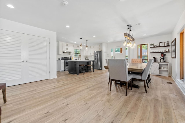 dining space with light hardwood / wood-style flooring and an inviting chandelier