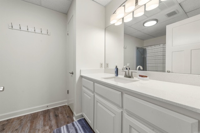 bathroom featuring vanity, walk in shower, hardwood / wood-style floors, and a paneled ceiling