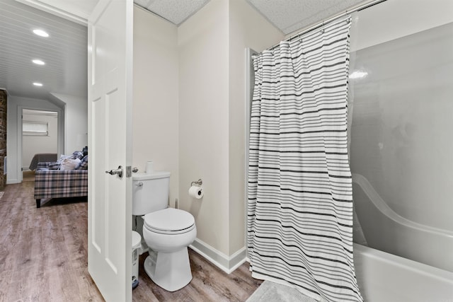 bathroom with shower / bath combo with shower curtain, hardwood / wood-style floors, and toilet