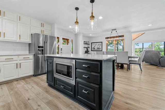 kitchen featuring light hardwood / wood-style floors, a kitchen island, stainless steel appliances, and white cabinets