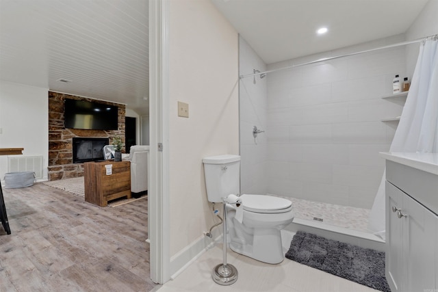 bathroom featuring a fireplace, vanity, a shower with shower curtain, hardwood / wood-style flooring, and toilet