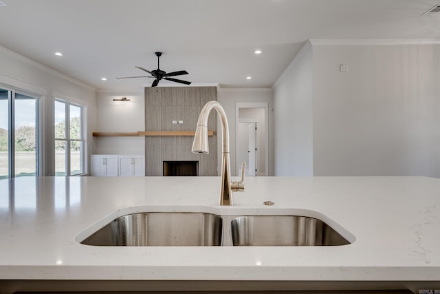 kitchen featuring ornamental molding, light stone countertops, and sink