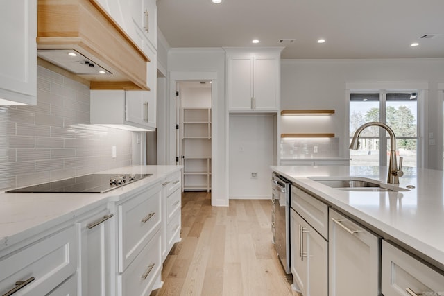 kitchen with white cabinetry, light wood-type flooring, black electric cooktop, custom range hood, and sink