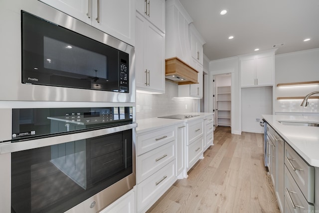 kitchen with appliances with stainless steel finishes, white cabinetry, sink, and light hardwood / wood-style floors