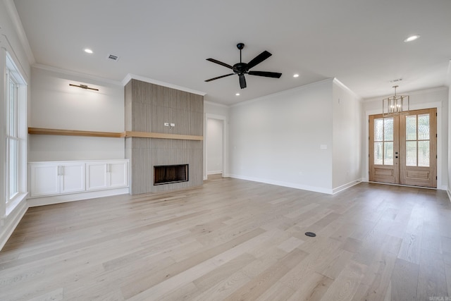 unfurnished living room featuring french doors, ornamental molding, a large fireplace, and light wood-type flooring