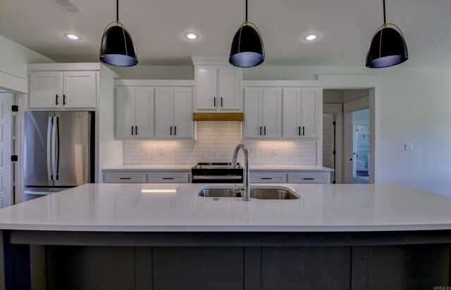 kitchen with white cabinets, a kitchen island with sink, appliances with stainless steel finishes, and sink