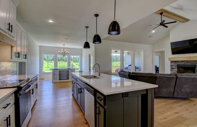 kitchen with vaulted ceiling with beams, sink, an island with sink, and white cabinets