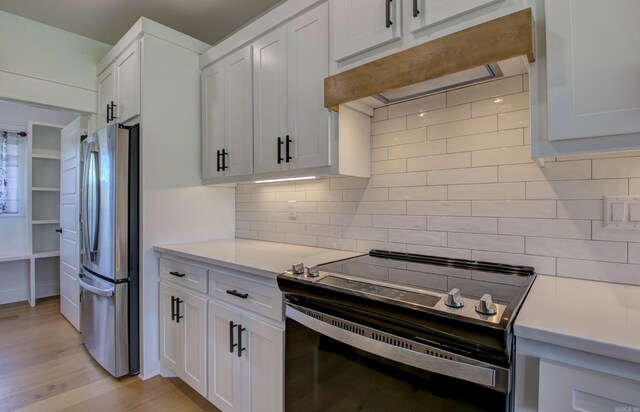 kitchen with stainless steel appliances, white cabinetry, light hardwood / wood-style floors, and tasteful backsplash