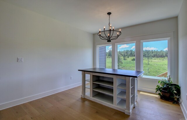 unfurnished dining area with light wood-type flooring and a notable chandelier