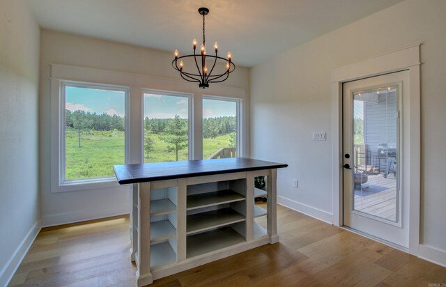 unfurnished dining area featuring an inviting chandelier and light hardwood / wood-style flooring