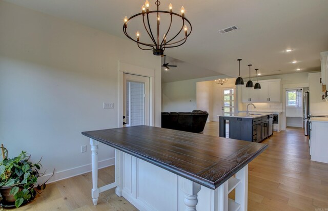 kitchen with white cabinets, sink, a large island, light hardwood / wood-style flooring, and appliances with stainless steel finishes