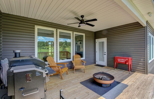 wooden terrace with ceiling fan, a grill, and an outdoor fire pit