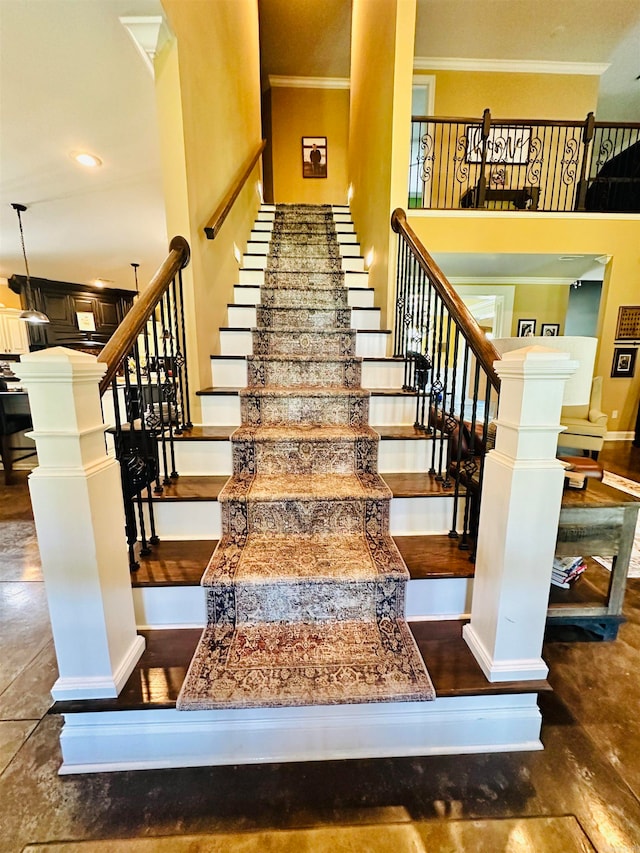 stairs featuring a high ceiling, decorative columns, hardwood / wood-style floors, and crown molding