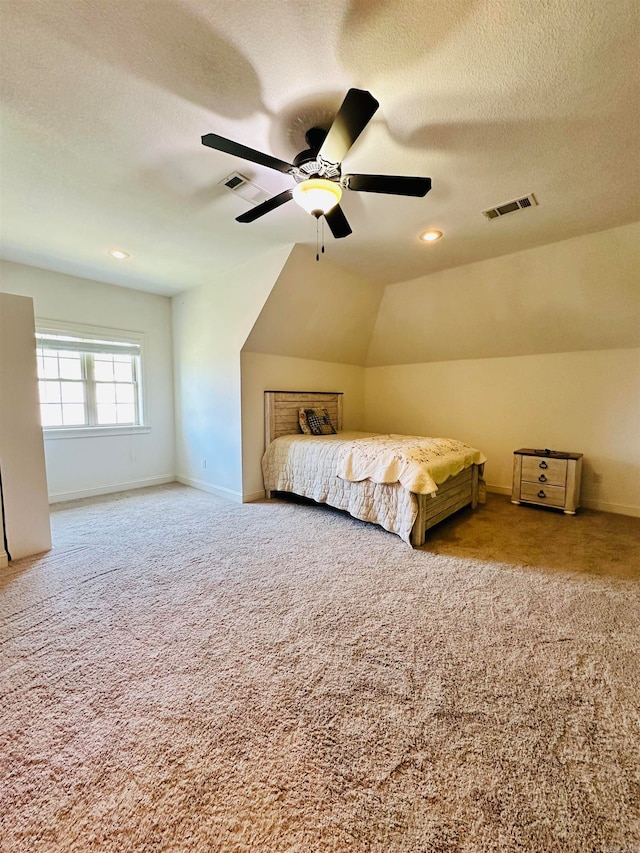 unfurnished bedroom with lofted ceiling, ceiling fan, carpet flooring, and a textured ceiling