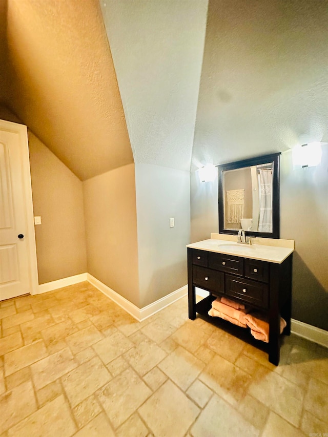 bathroom with lofted ceiling, a textured ceiling, and vanity