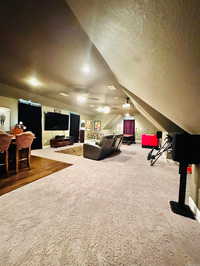 recreation room featuring ceiling fan, a textured ceiling, lofted ceiling, and carpet flooring