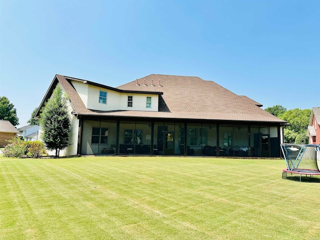 back of house featuring a trampoline and a lawn