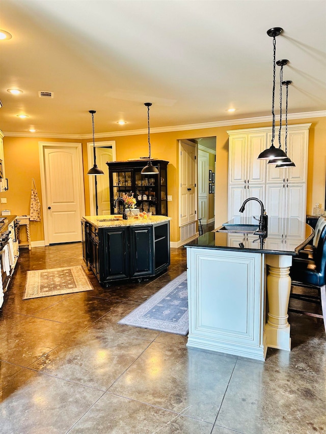 kitchen featuring decorative light fixtures, a kitchen island with sink, crown molding, and sink