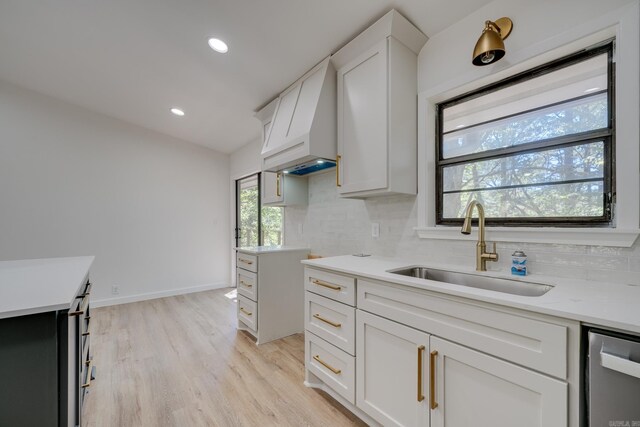 kitchen featuring decorative backsplash, white cabinets, light wood-type flooring, and sink