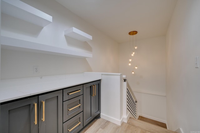 bar featuring light hardwood / wood-style floors, light stone countertops, and gray cabinets