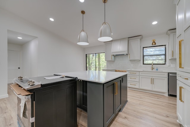 kitchen with a kitchen island, white cabinetry, light hardwood / wood-style flooring, and decorative light fixtures