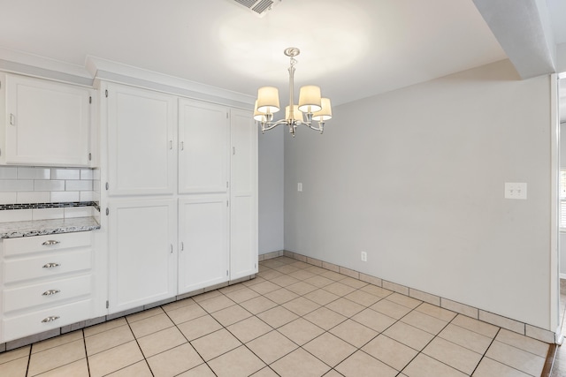 kitchen with white cabinets, decorative backsplash, an inviting chandelier, decorative light fixtures, and light stone countertops