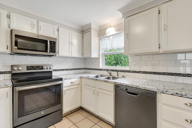 kitchen with appliances with stainless steel finishes, light tile patterned flooring, sink, and white cabinets