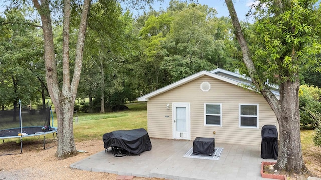 view of outbuilding featuring a trampoline and a lawn