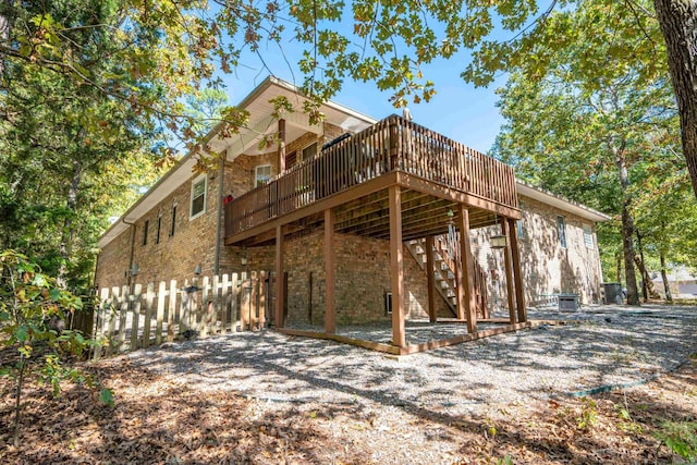 exterior space with fence, stairs, a deck, and brick siding