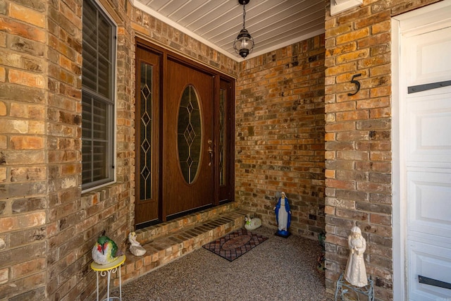 view of exterior entry with covered porch and brick siding