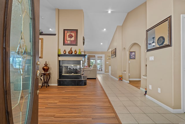 entrance foyer with baseboards, recessed lighting, a multi sided fireplace, high vaulted ceiling, and light wood finished floors