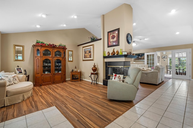 tiled living room featuring a glass covered fireplace, recessed lighting, baseboards, and vaulted ceiling