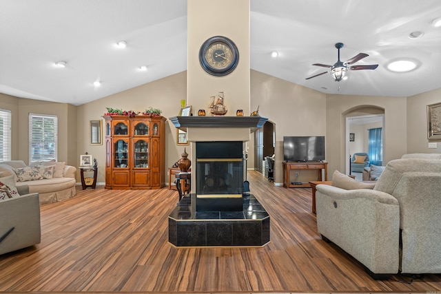 living room featuring vaulted ceiling, a multi sided fireplace, ceiling fan, arched walkways, and wood finished floors