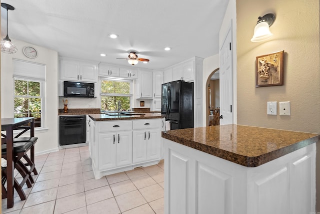kitchen featuring arched walkways, a healthy amount of sunlight, dark countertops, and black appliances
