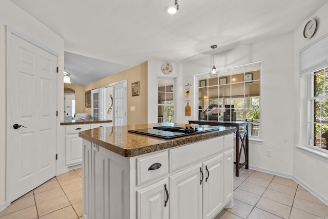 kitchen with black electric stovetop, light tile patterned floors, dark countertops, and a kitchen island