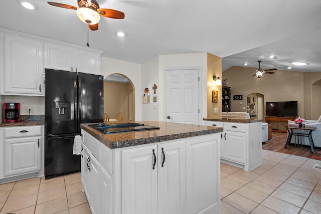 kitchen featuring arched walkways, a ceiling fan, black appliances, and a center island